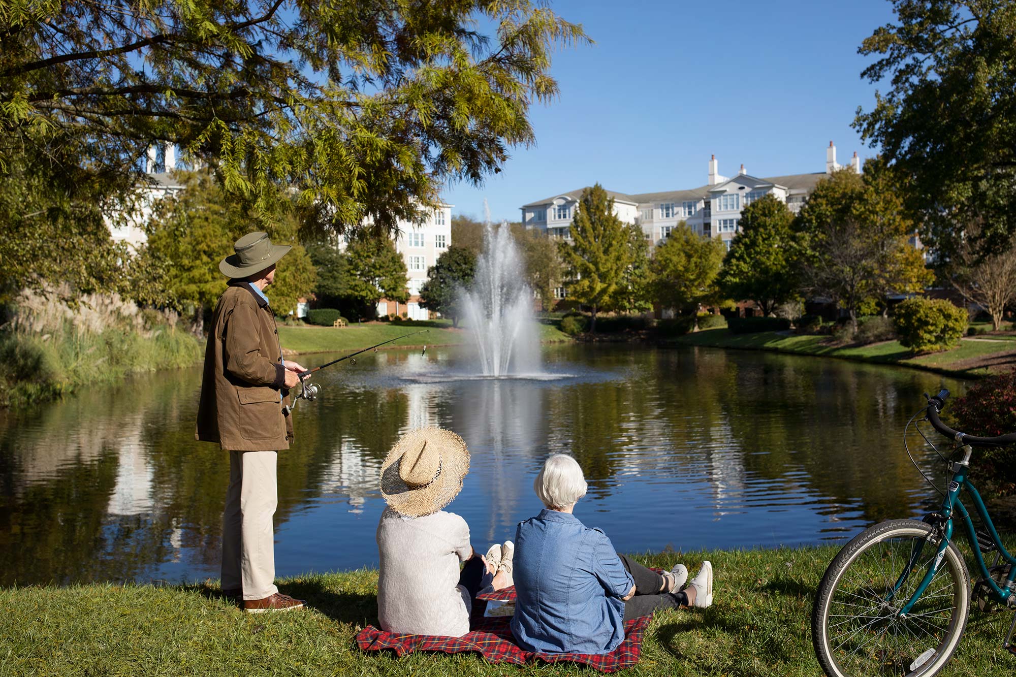 three people sitting by the pond